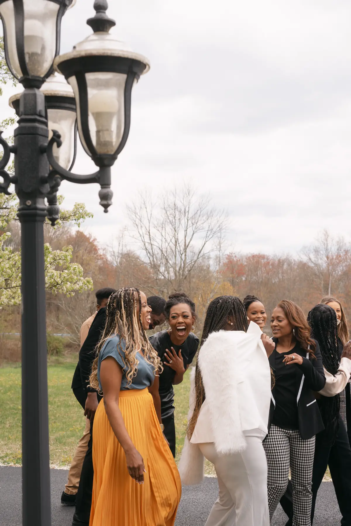 Women in gold and ivory walk together under autumn trees.