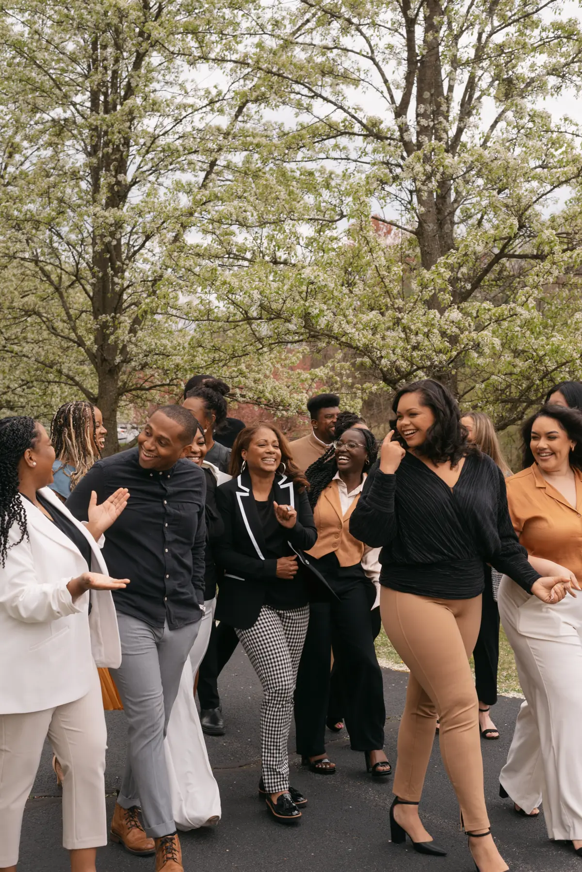 A group walks down a tree-lined road together, smiling.