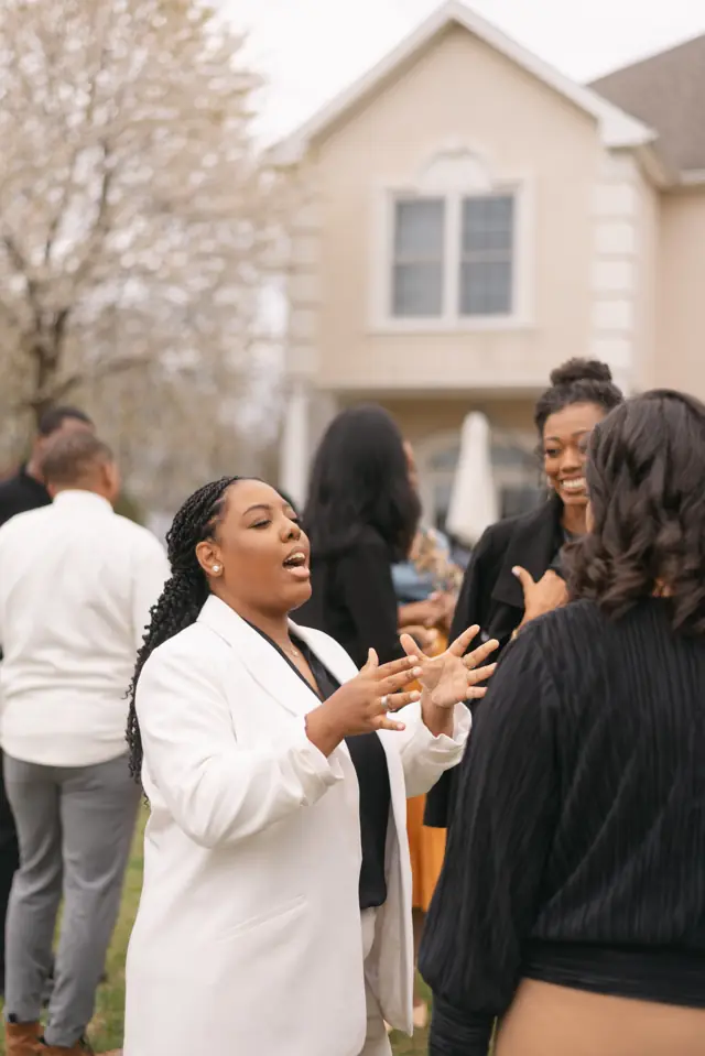 Apostle Nicole Olaniyi, in a white blazer, talks with the women outside the retreat house.